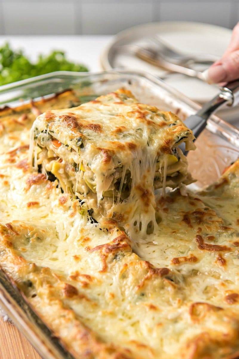 using spatula to lift out a piece of lasagna out of the pan