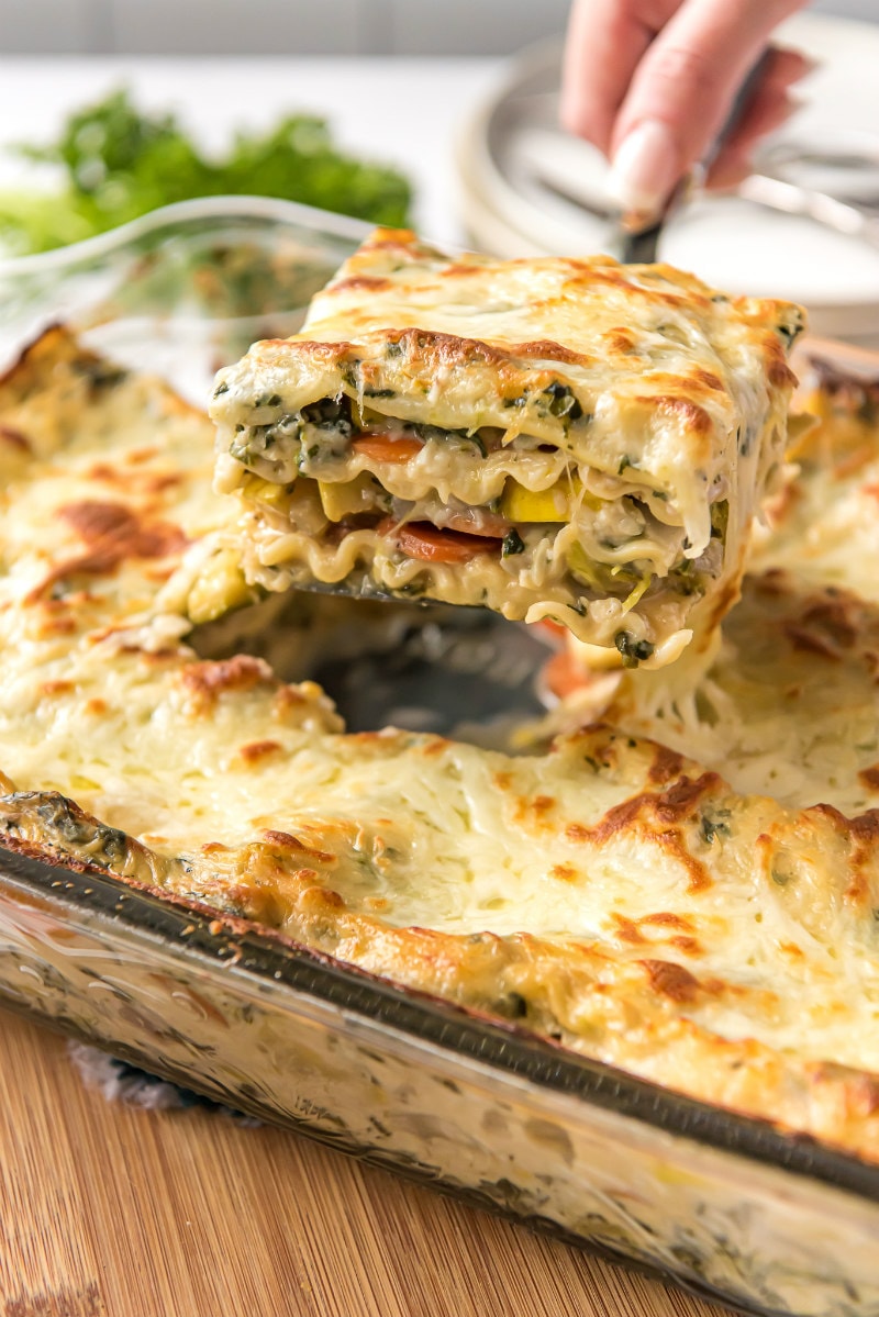 serving garden vegetable lasagna out of the pan with a spatula