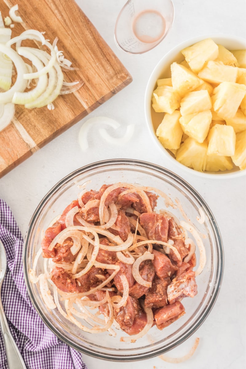 marinated pork in a bowl with pineapple in another bowl