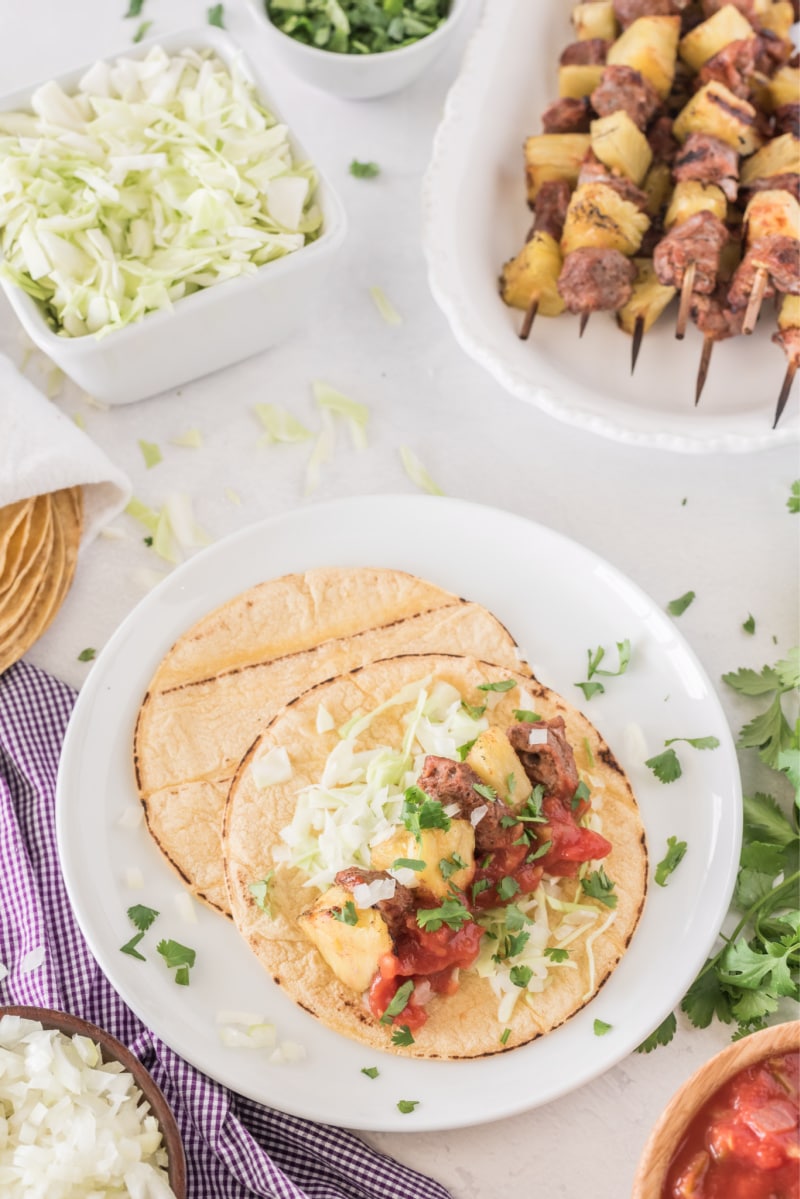 grilled pork and pineapple soft tacos on a white plate