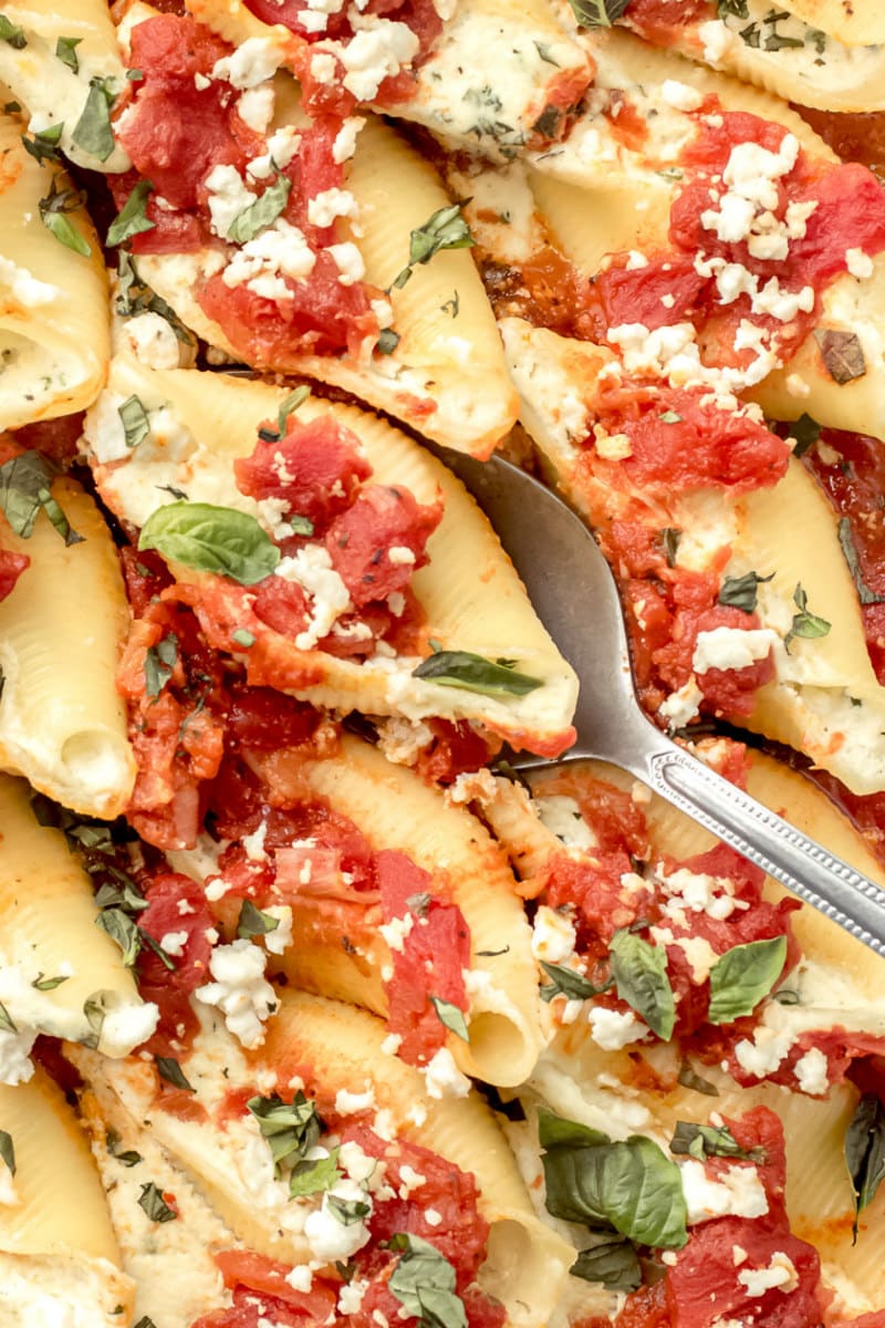 spooning out pasta shells filled with feta and herbs