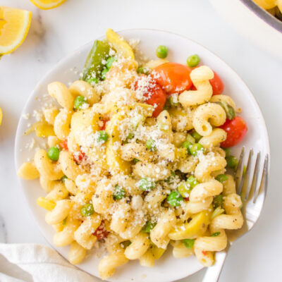 pasta with spring vegetables topped with Parmesan on a plate