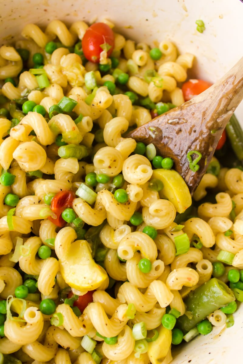 spooning out pasta with veggies out of pan