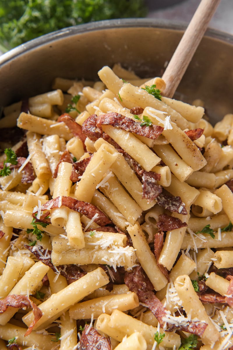 dishing out serving of ziti carbonara from a skillet