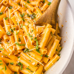 spooning ziti with vodka sauce out of skillet