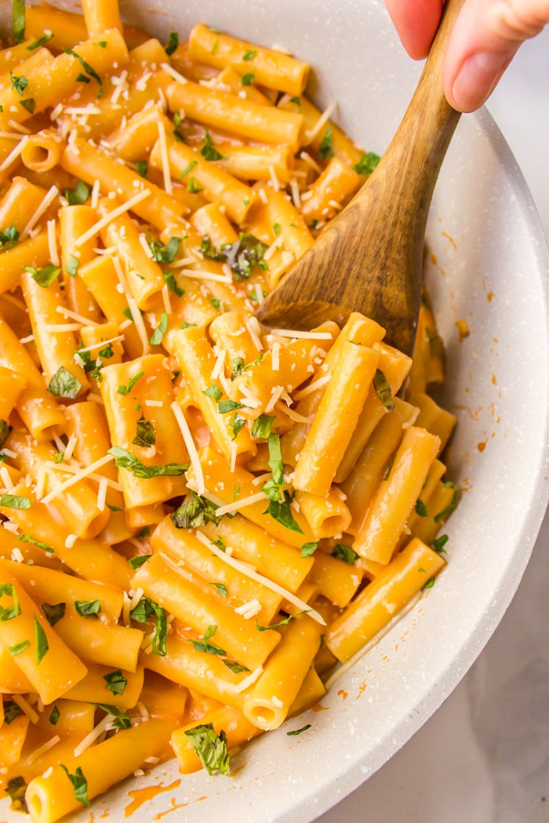 spooning ziti with vodka sauce out of skillet