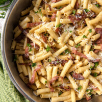 ziti carbonara in a skillet - green cloth napkin and fresh parsley on the side