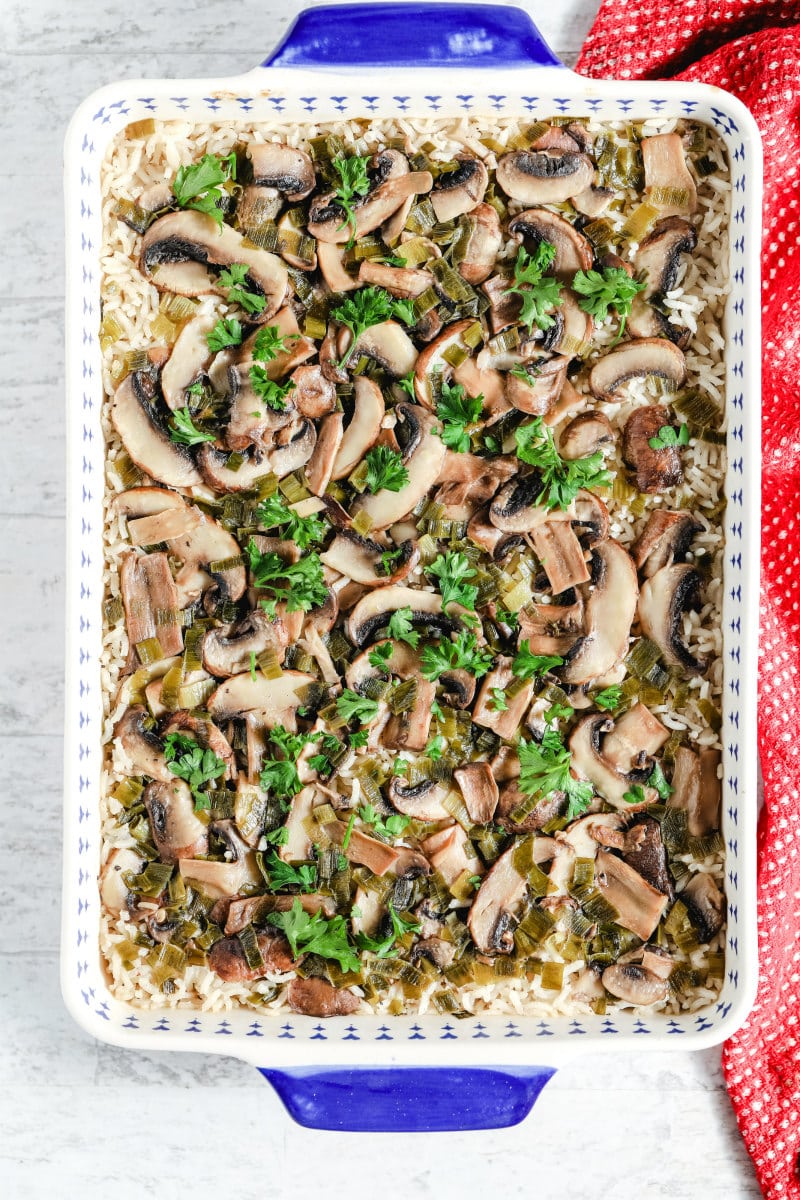 overhead shot of baked mushroom rice in a blue and white casserole dish with a red cloth napkin on the side