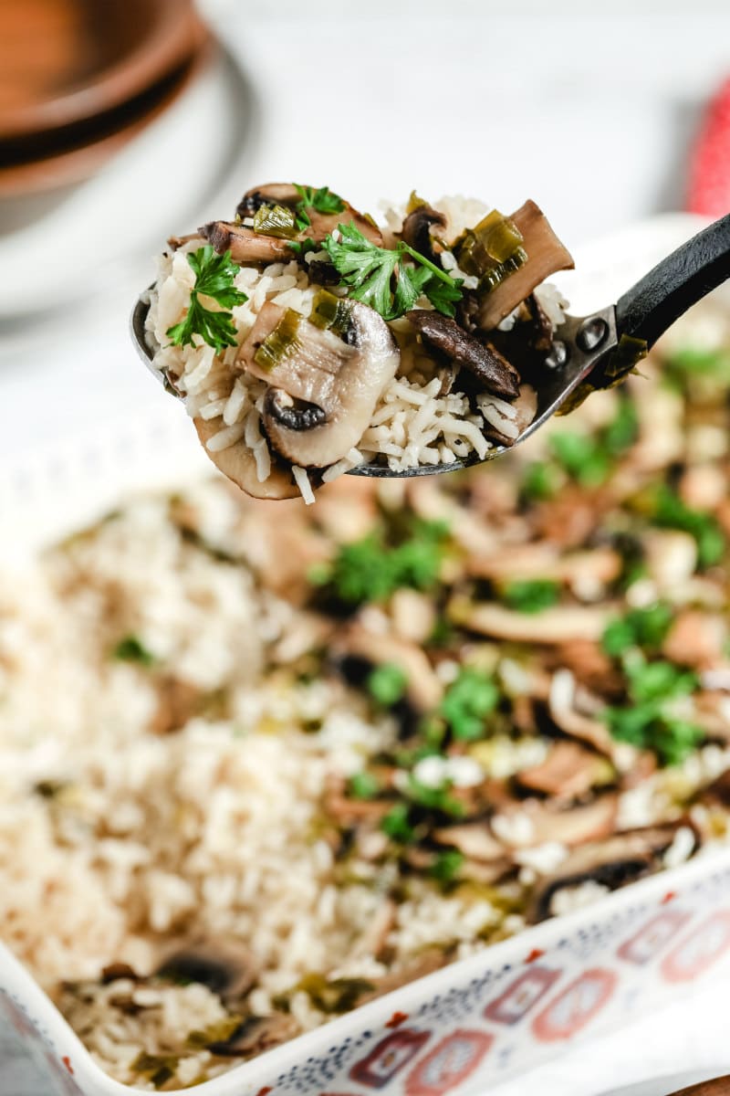 spoonful of baked mushroom rice over a casserole dish of rice