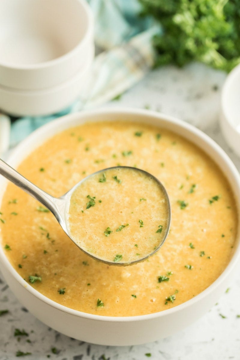 ladle of butternut squash soup above bowl