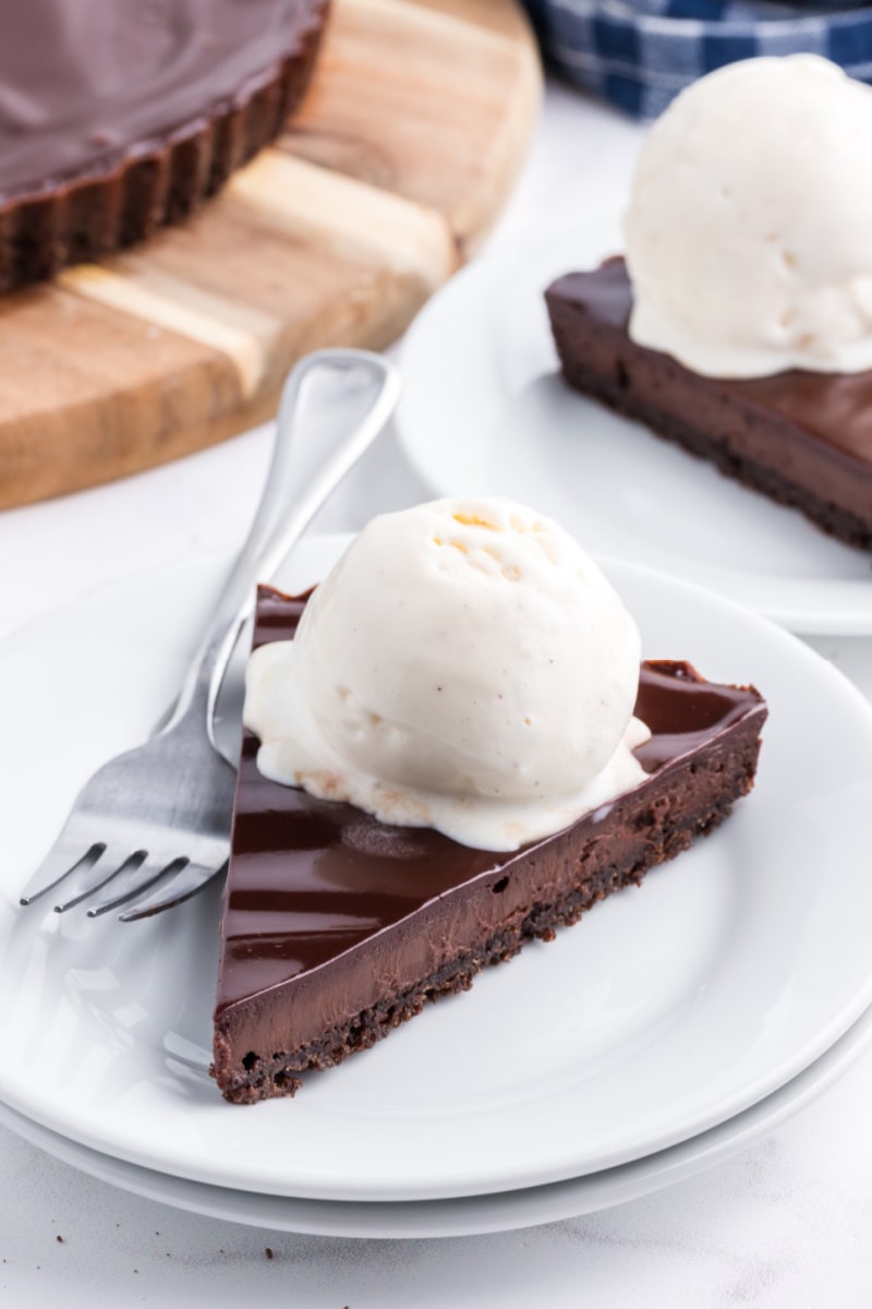 chocolate glazed chocolate tart slice with vanilla ice cream on plate