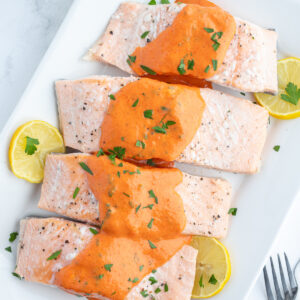 four pieces of cold poached salmon with mustard sauce on top