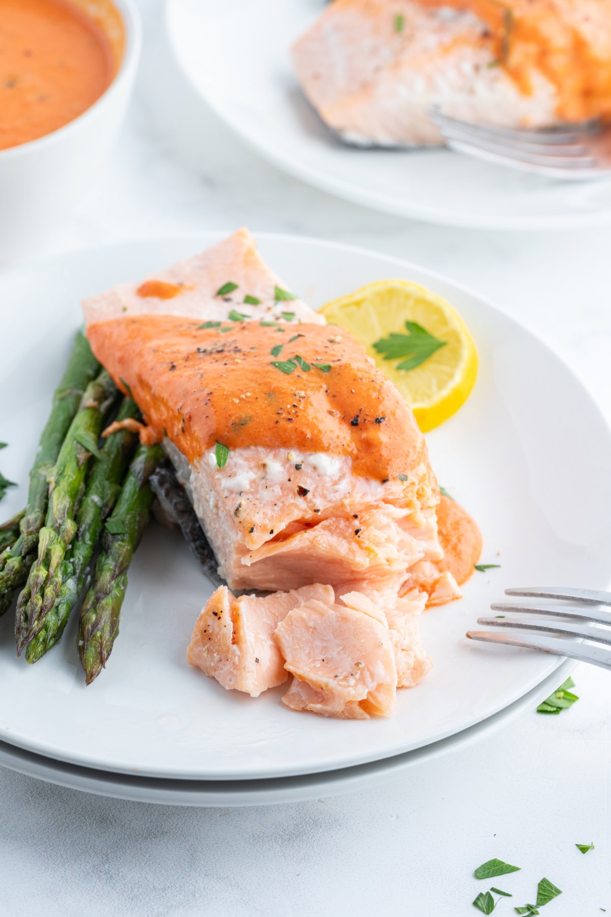 Summertime is the perfect time to serve up this Cold Poached Salmon recipe. It's delicious with a side of roasted red pepper- mustard sauce. cold poached salmon with mustard sauce on plate with fork opening salmon filet