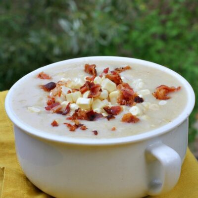 white bowl of fresh corn chowder with bacon on top set on a yellow napkin