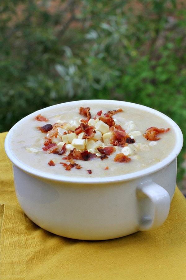 white bowl of fresh corn chowder with bacon on top set on a yellow napkin