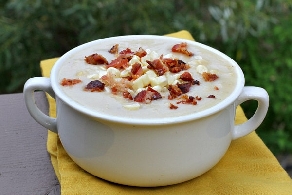 white bowl of fresh corn chowder with bacon on top set on a yellow napkin