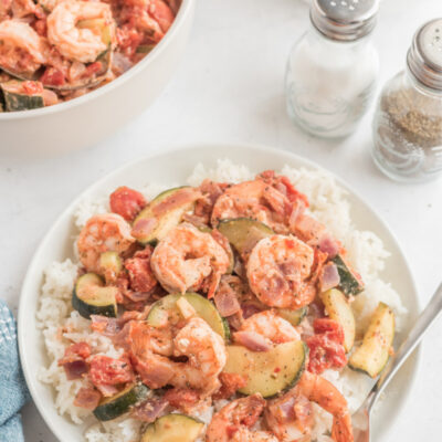 greek style shrimp over rice on a white plate