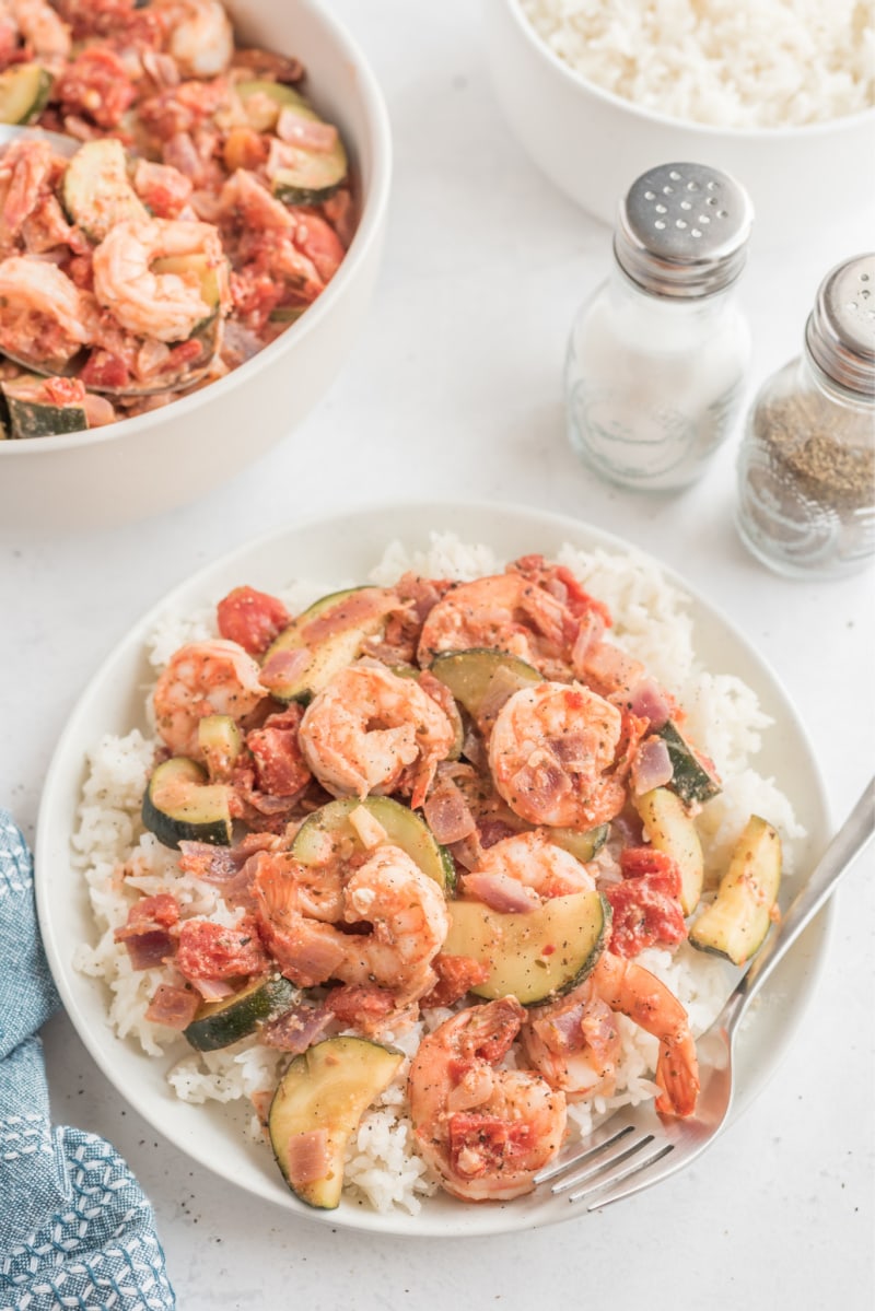 greek style shrimp over rice on a white plate