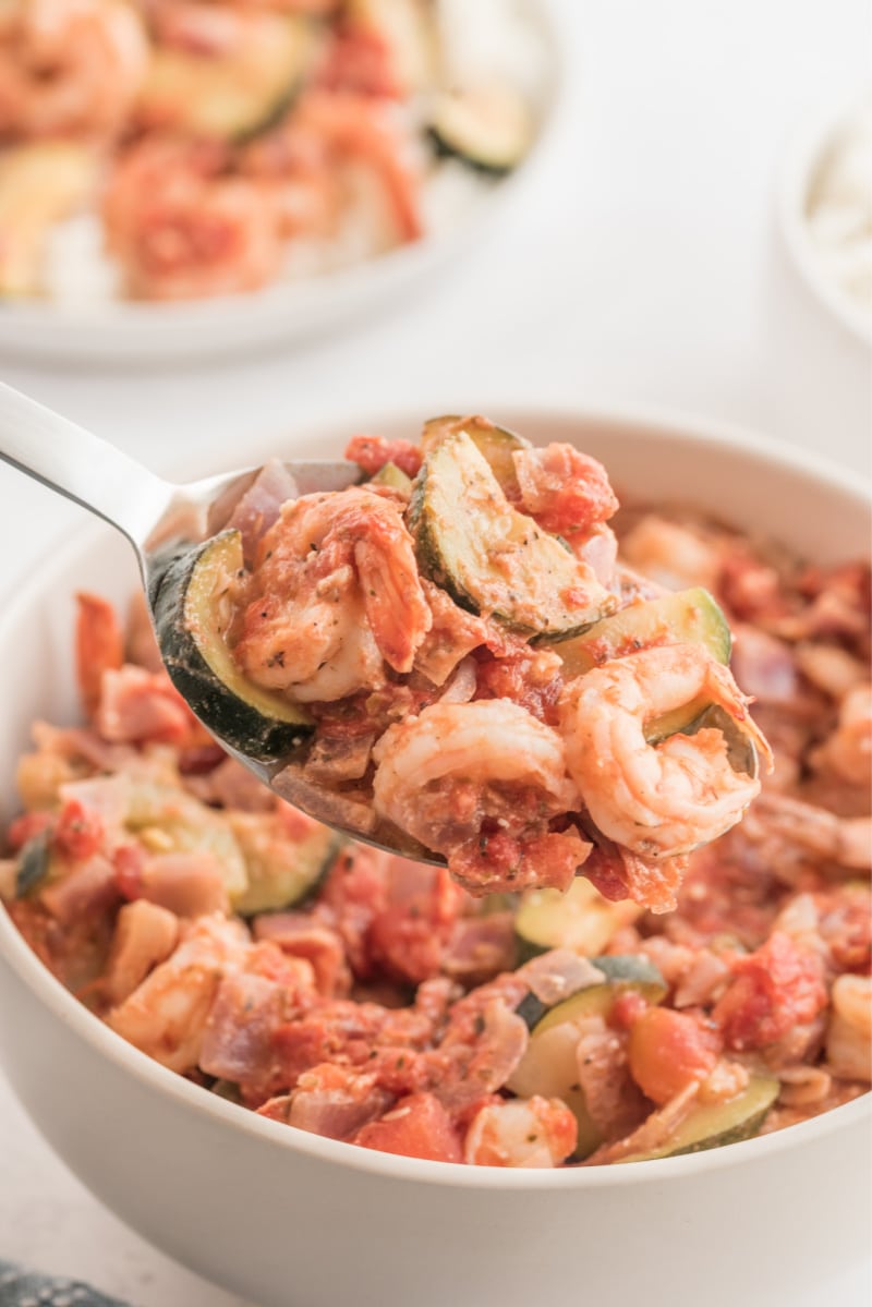 spooning out greek style shrimp out of white bowl