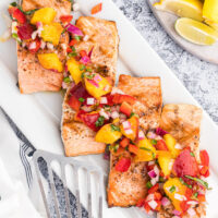grilled salmon fillets on a platter topped with nectarine salsa