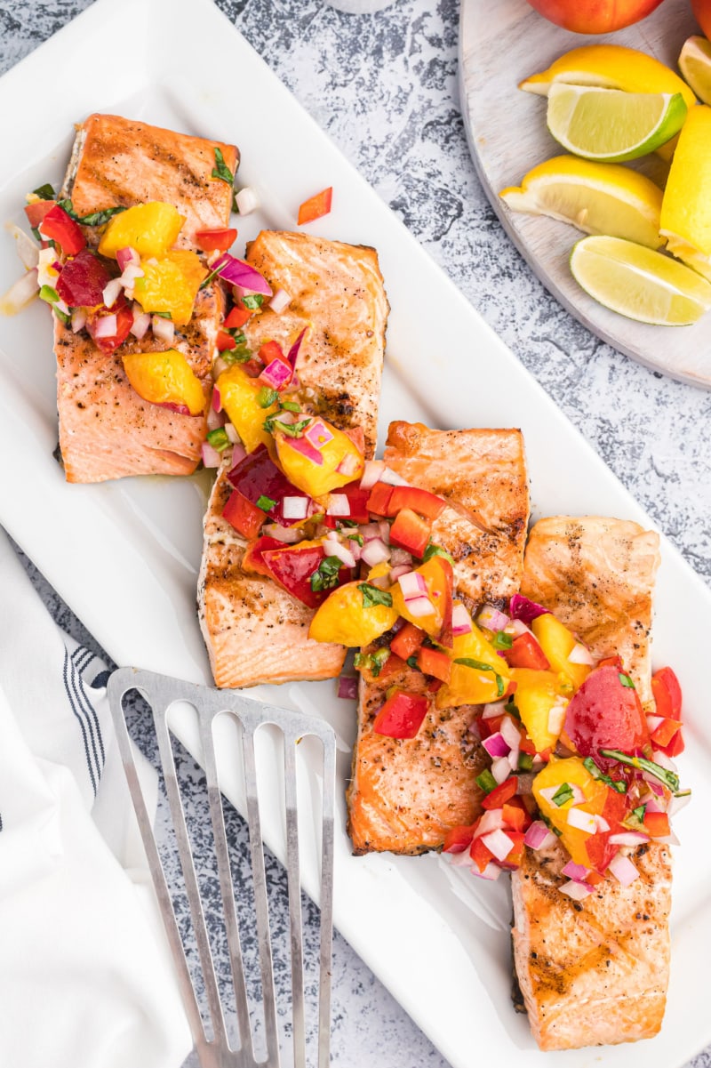 grilled salmon fillets on a platter topped with nectarine salsa