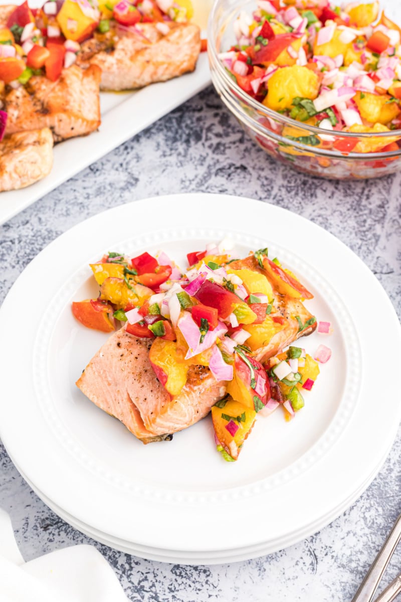 salmon fillet on a white plate topped with nectarine salsa