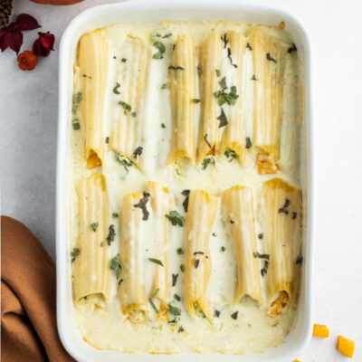 pumpkin manicotti with bechamel sauce in white casserole dish