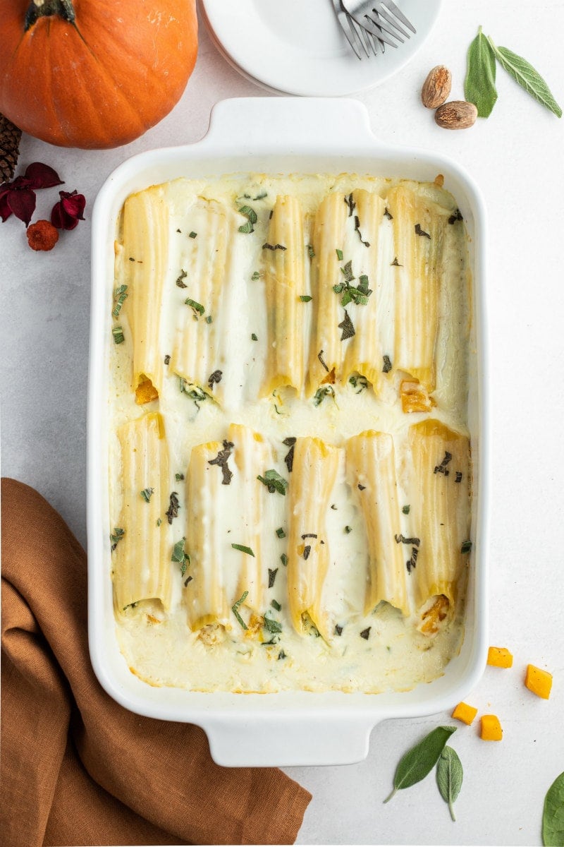 pumpkin manicotti with bechamel sauce in white casserole dish