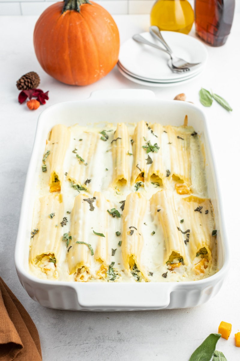 pumpkin manicotti with bechamel sauce in a white casserole dish