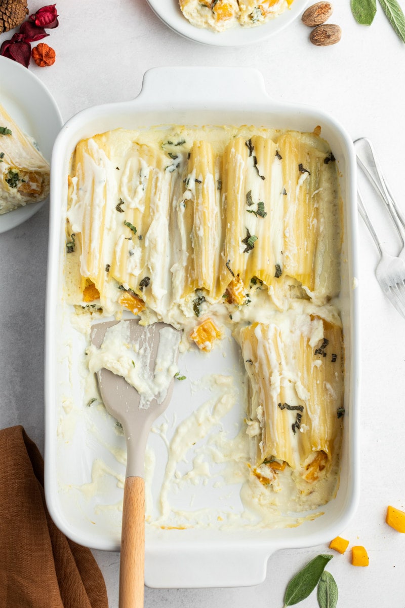 pumpkin manicotti being served out of a white casserole dish