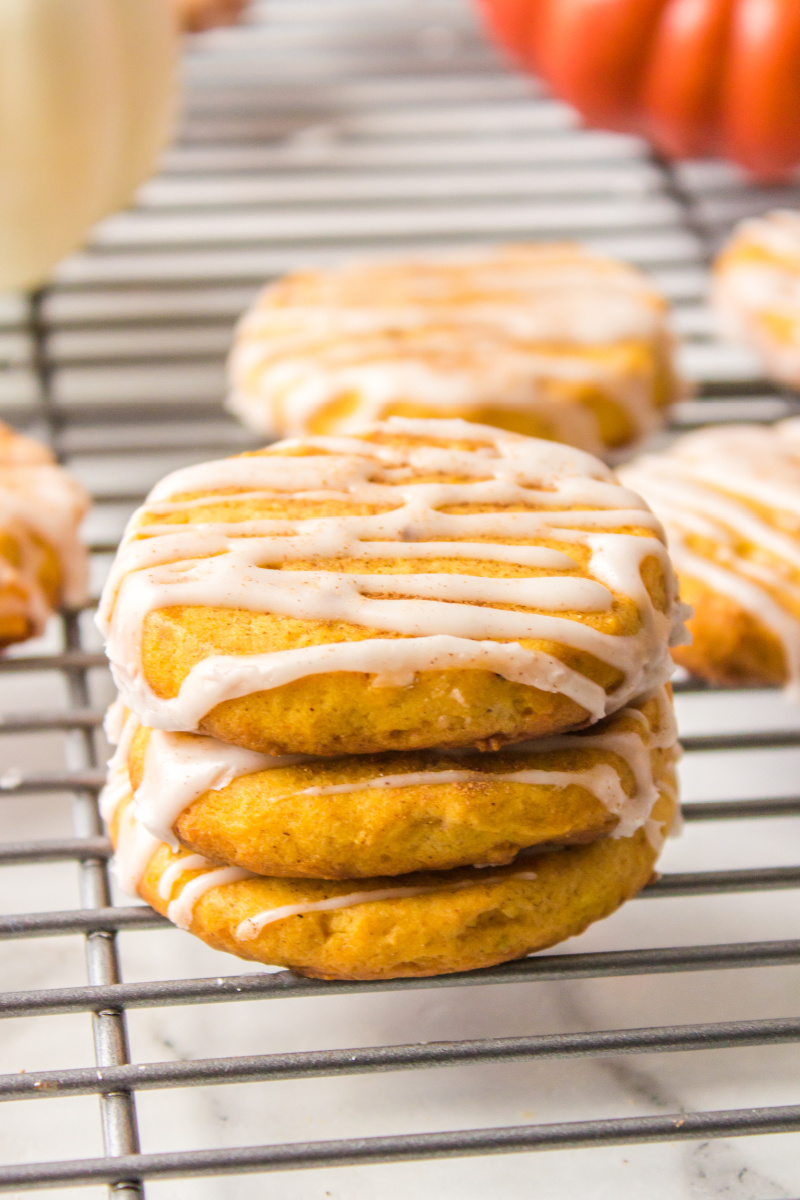 stack of three pumpkin shortbread cookies on a cooling rack
