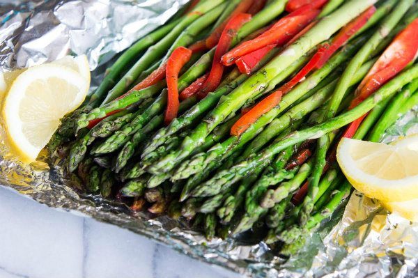 Red Pepper Confetti Asparagus on a platter with lemon wedges