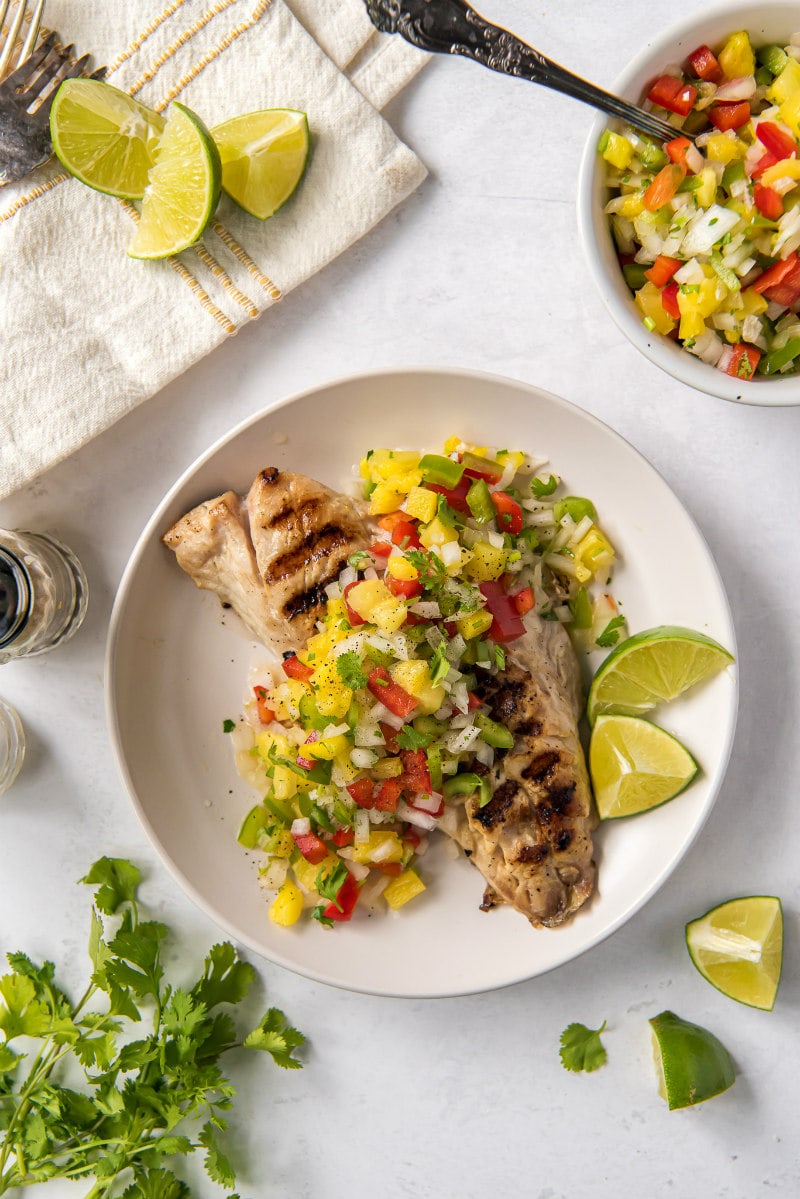 overhead shot of red snapper with pineapple salsa on a white plate