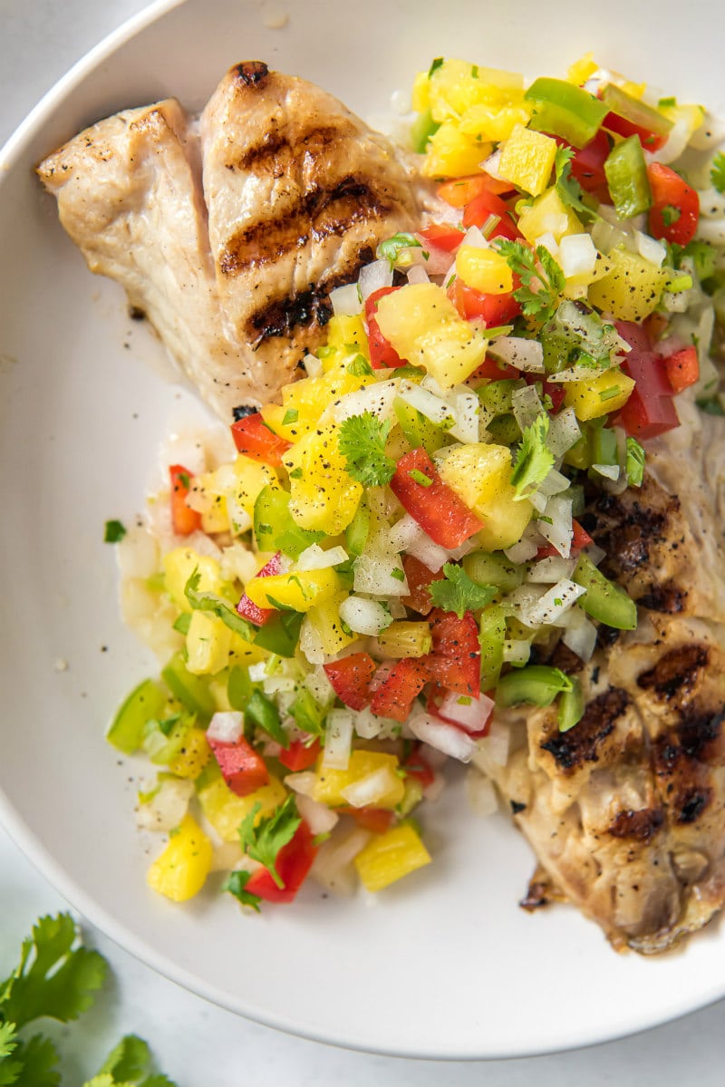 red snapper with pineapple salsa on a white plate