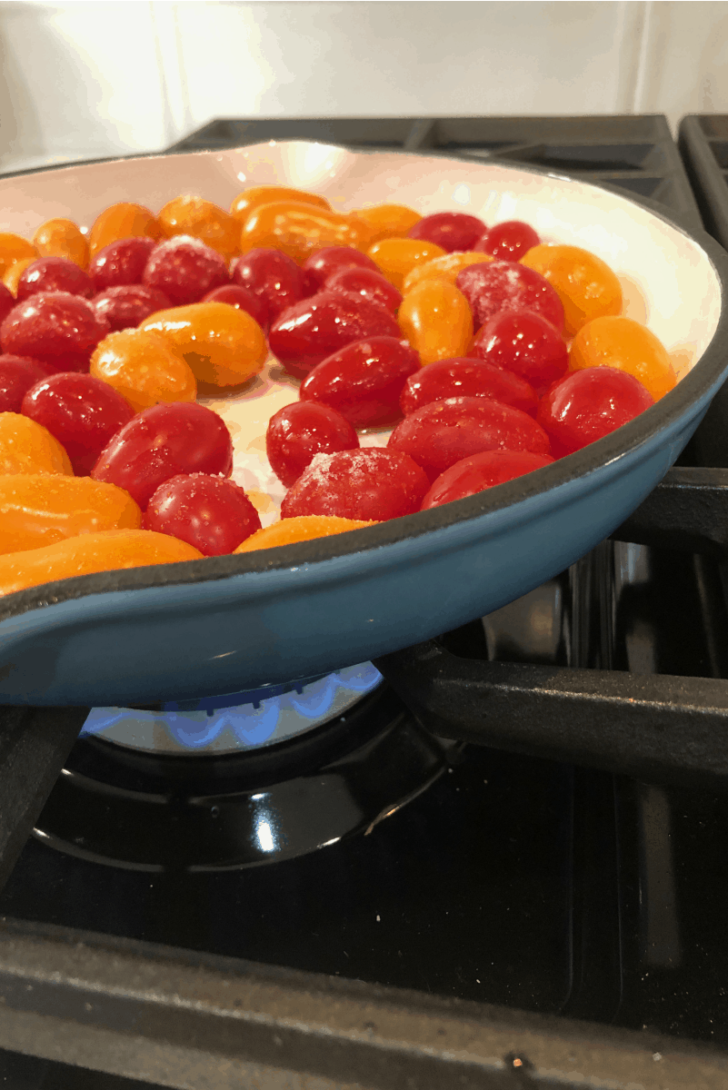 cherry tomatoes in a skillet over flame