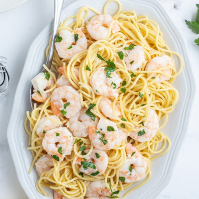 shrimp scampi on a platter over pasta