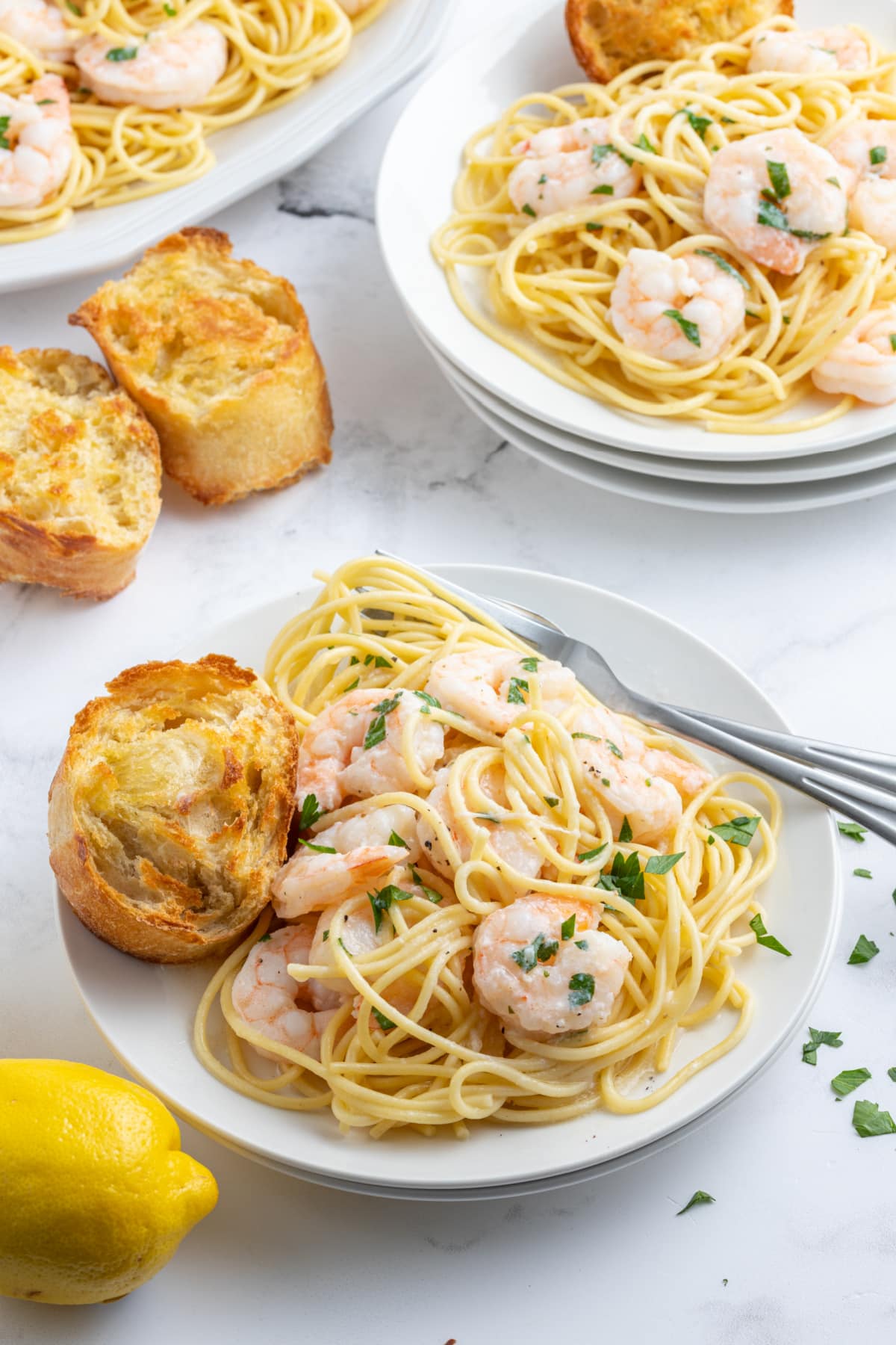 shrimp scampi serving on plate with pasta and bread