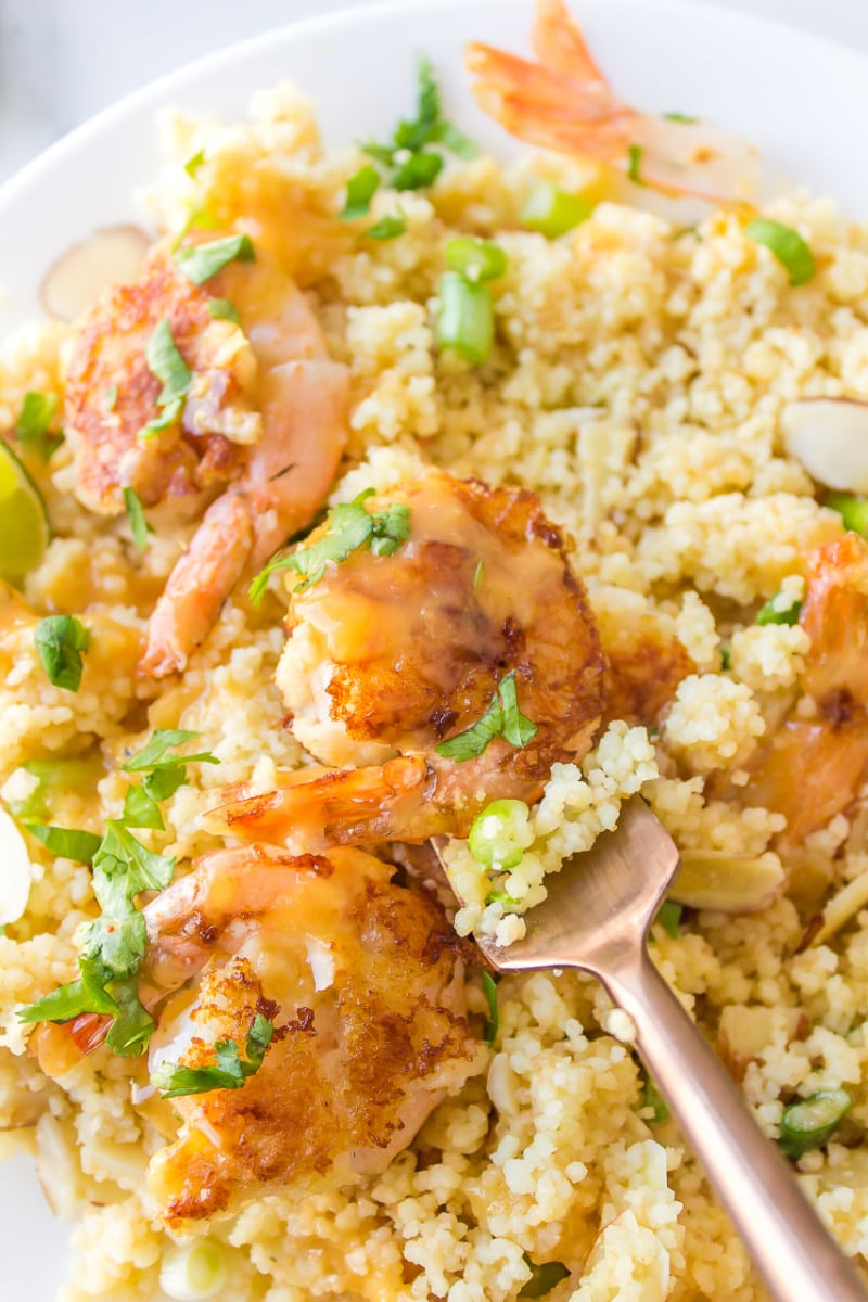 fork full of shrimp with couscous and ginger orange sauce