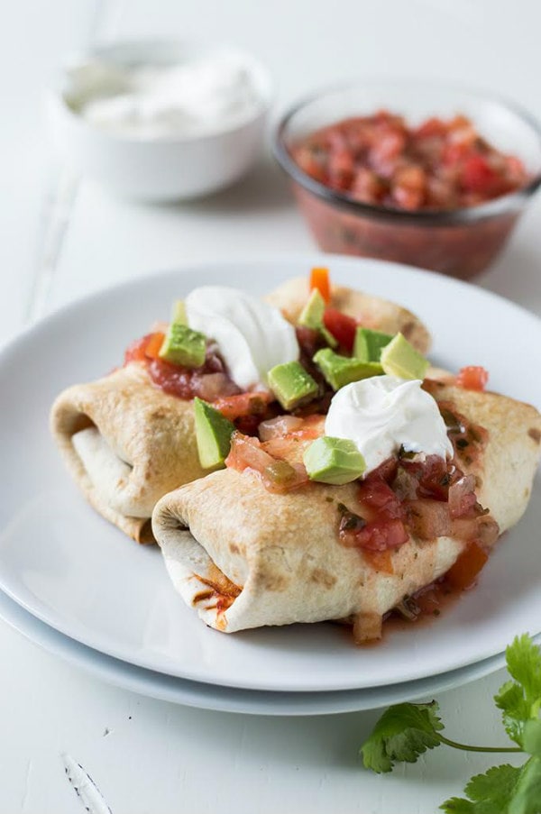 Skinny Chimichangas on a white plate with salsa sour cream and avocado