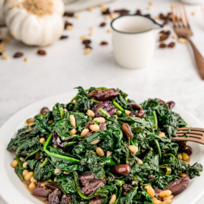 plate of spinach with olives raisins and pine nuts