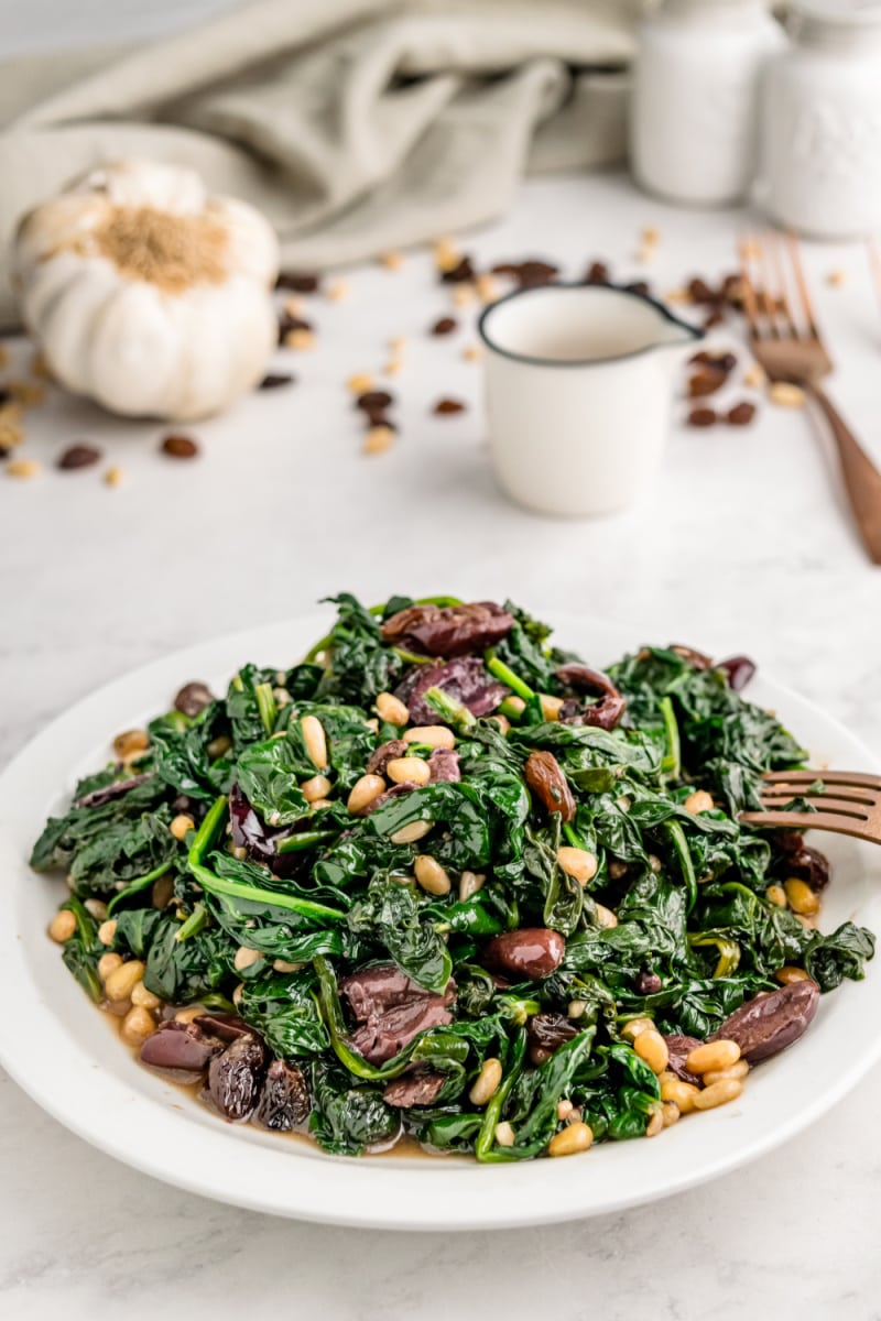 Spinach with Olives, Raisins and Pine Nuts recipe from RecipeGirl.com #spinach #olives #raisins #pinenuts #recipe #RecipeGirl plate of spinach with olives raisins and pine nuts