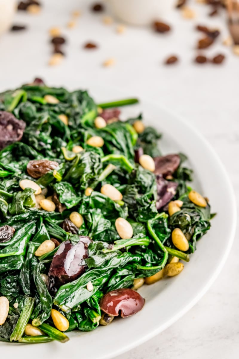 Spinach with Olives, Raisins and Pine Nuts recipe from RecipeGirl.com #spinach #olives #raisins #pinenuts #recipe #RecipeGirl plate of spinach with olives raisins and pine nuts