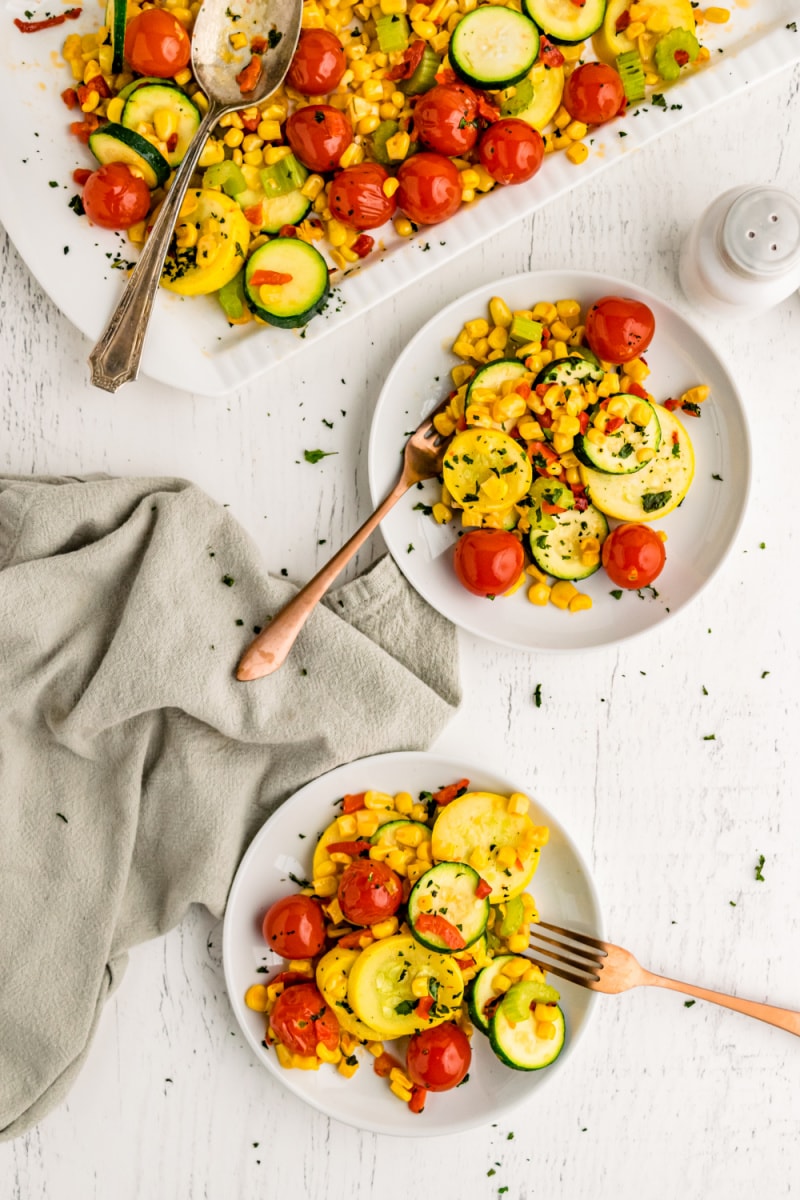 servings of summer squash and cherry tomatoes on white plates