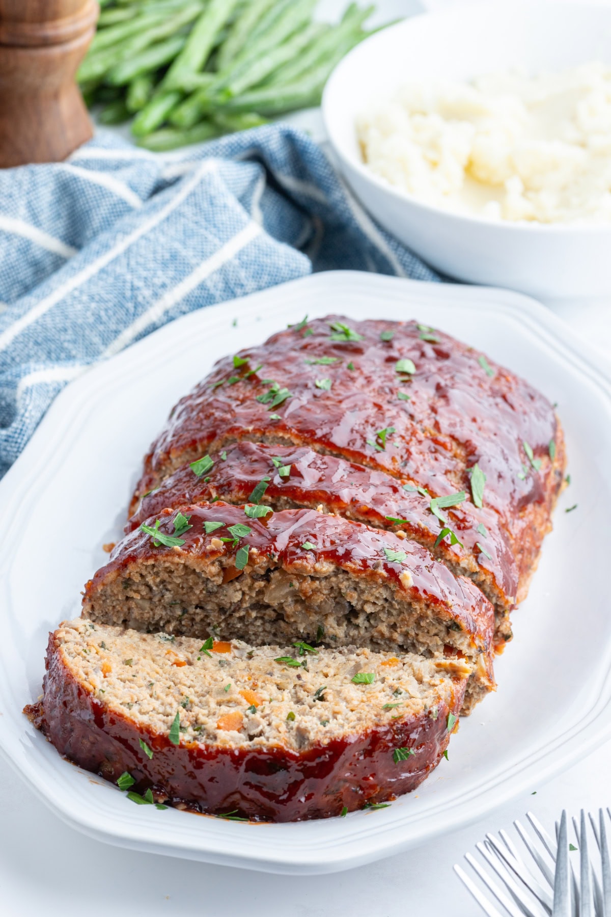 Moist Ground Turkey Meatloaf made with lean turkey, veggies, and BBQ sauce for flavor. Healthy, high protein, and never dry. Easy weeknight dinner recipe. ground turkey meatloaf on platter sliced open to see the inside
