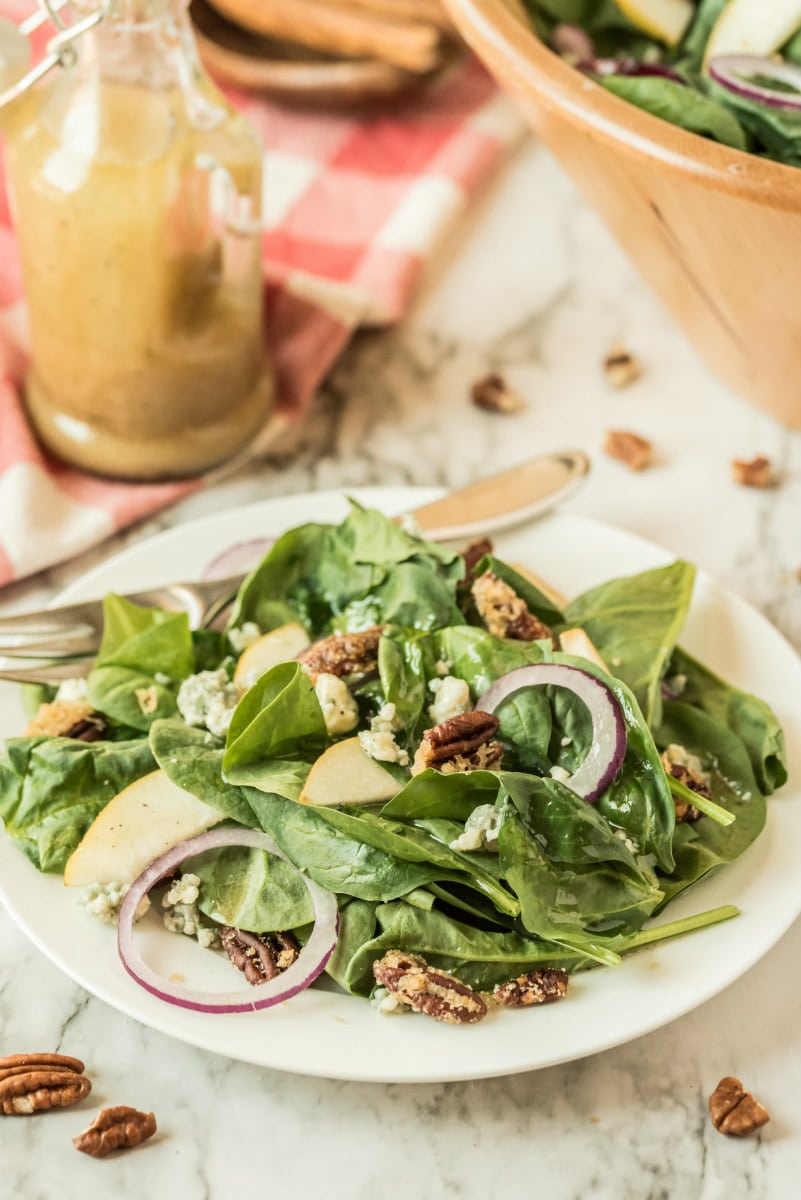 salad on white plate with jar of dressing in background