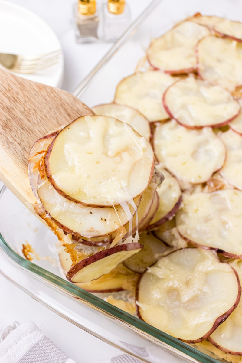 spooning scalloped potatoes out of pan