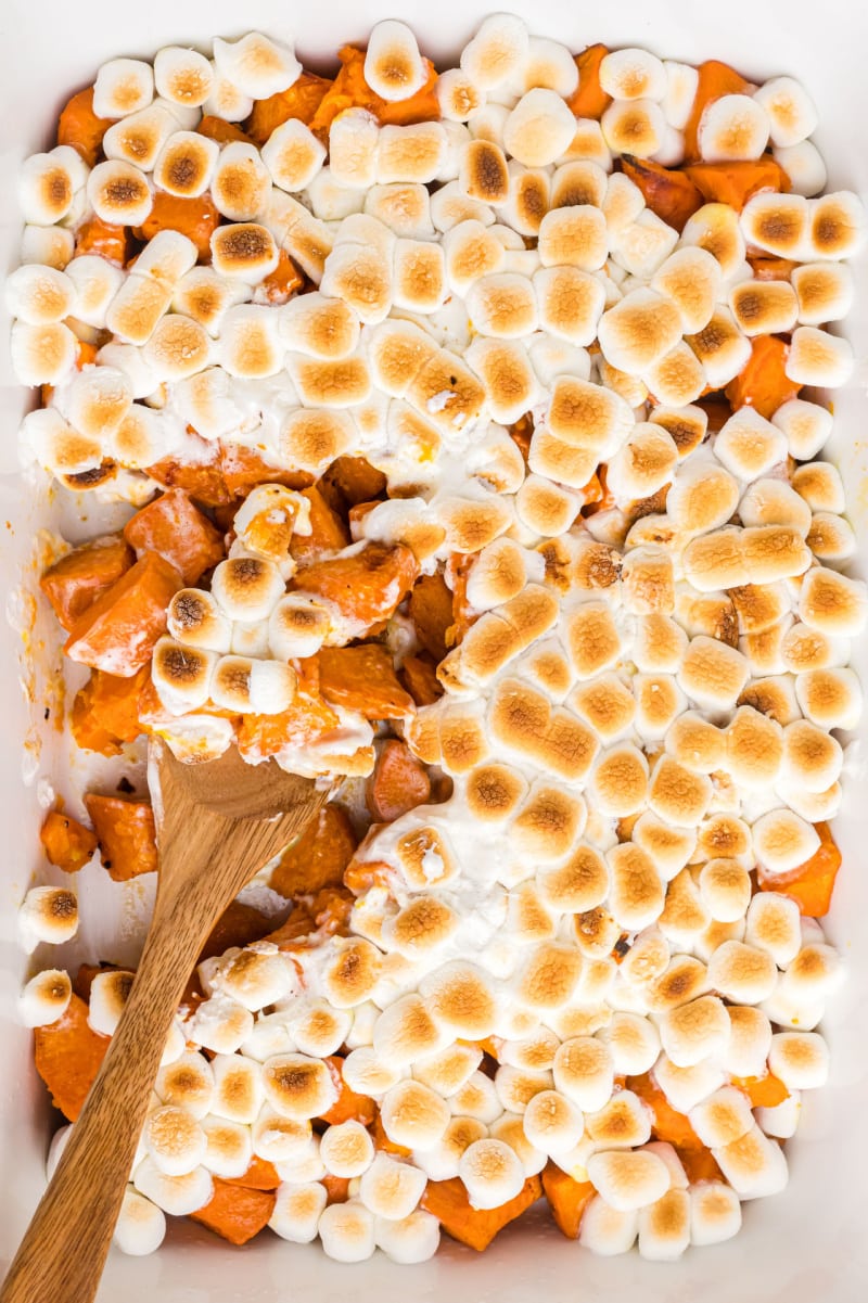 spooning out caramelized yams with marshmallows