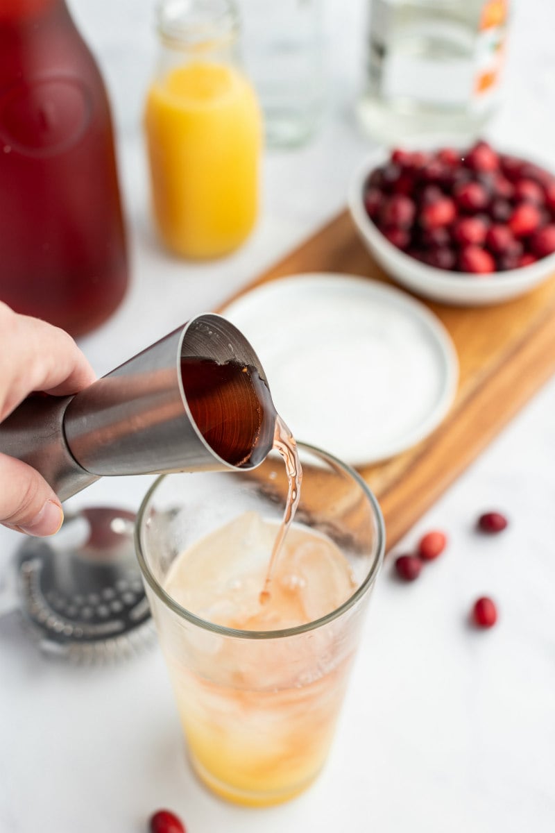 pouring ingredients into shaker for cranberry margarita