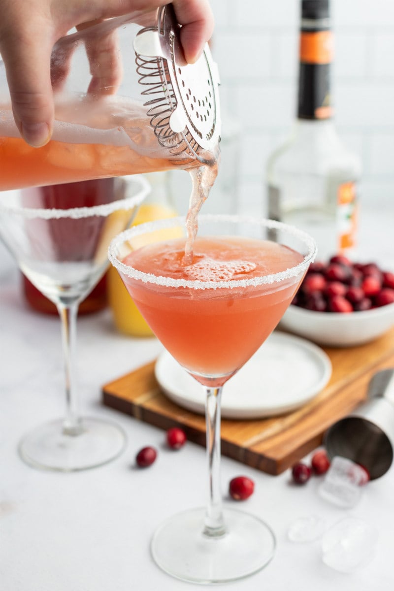 pouring cranberry margarita into glass