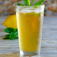 Sweet Summer Iced Tea garnished with fresh mint with a fresh lemon in the background